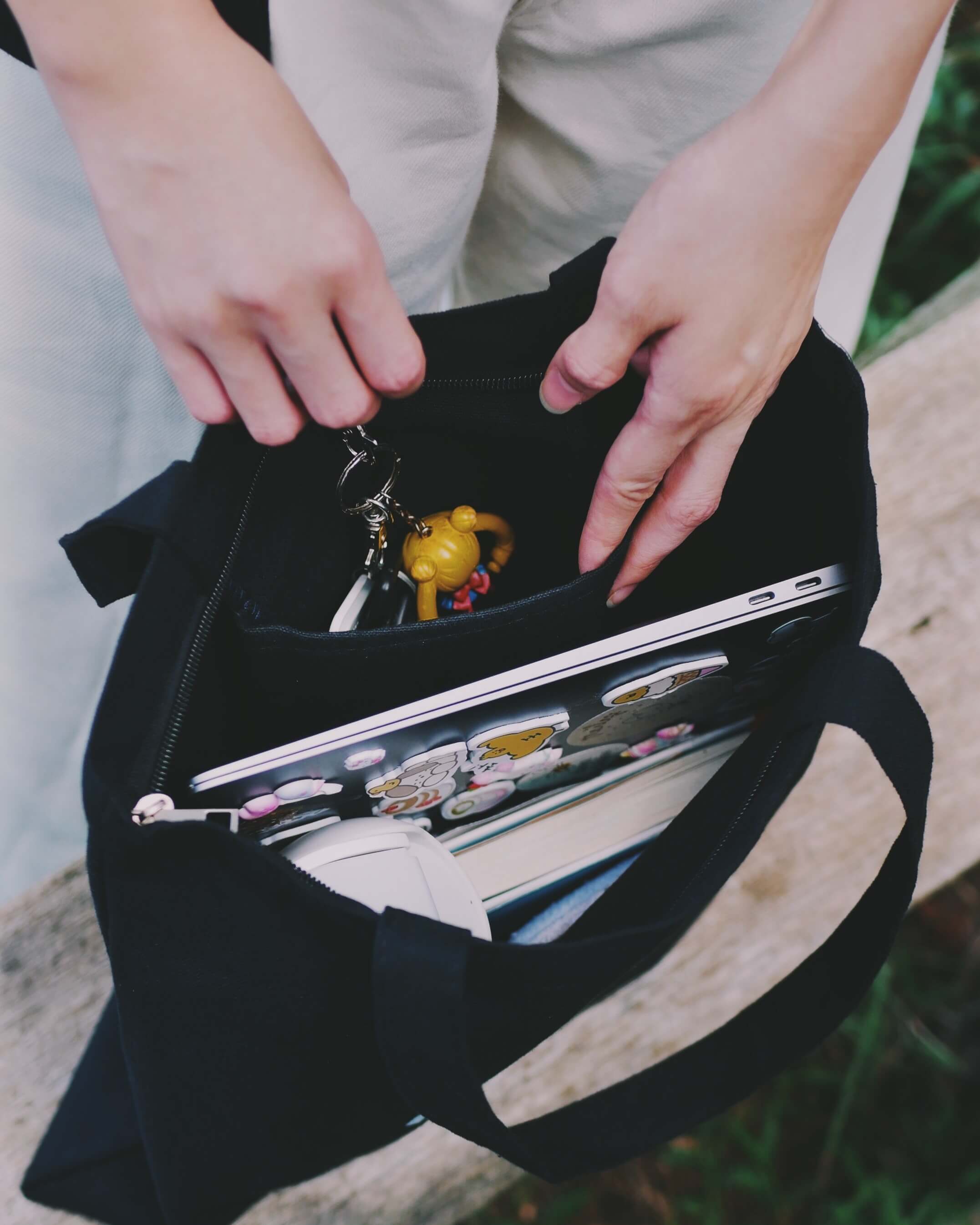 Person putting keys in a pocket of a black tote bag