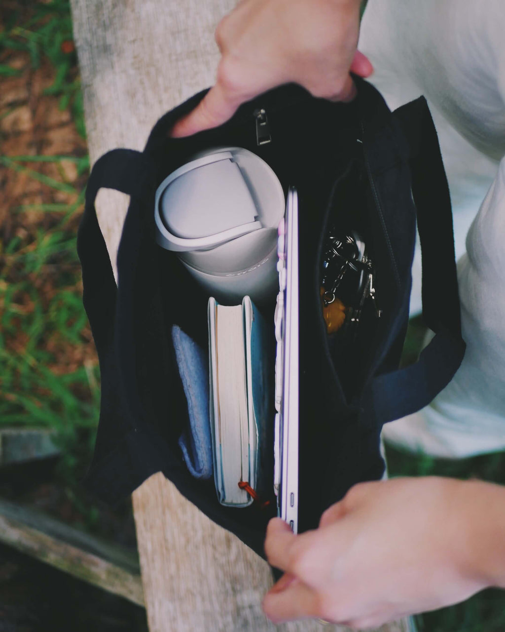 Person holding a black tote bag while showing it's interior