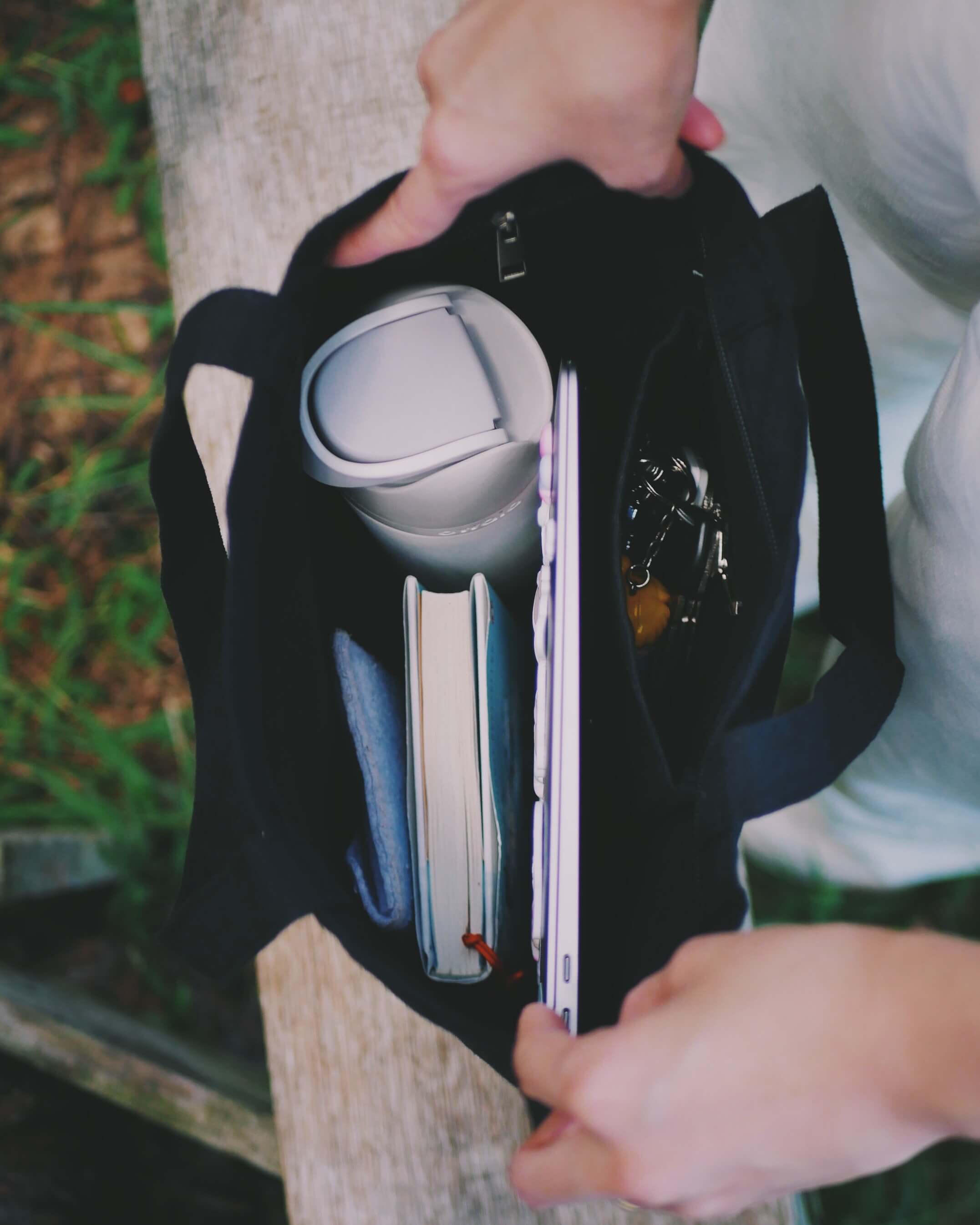 Person holding a black tote bag while showing it's interior