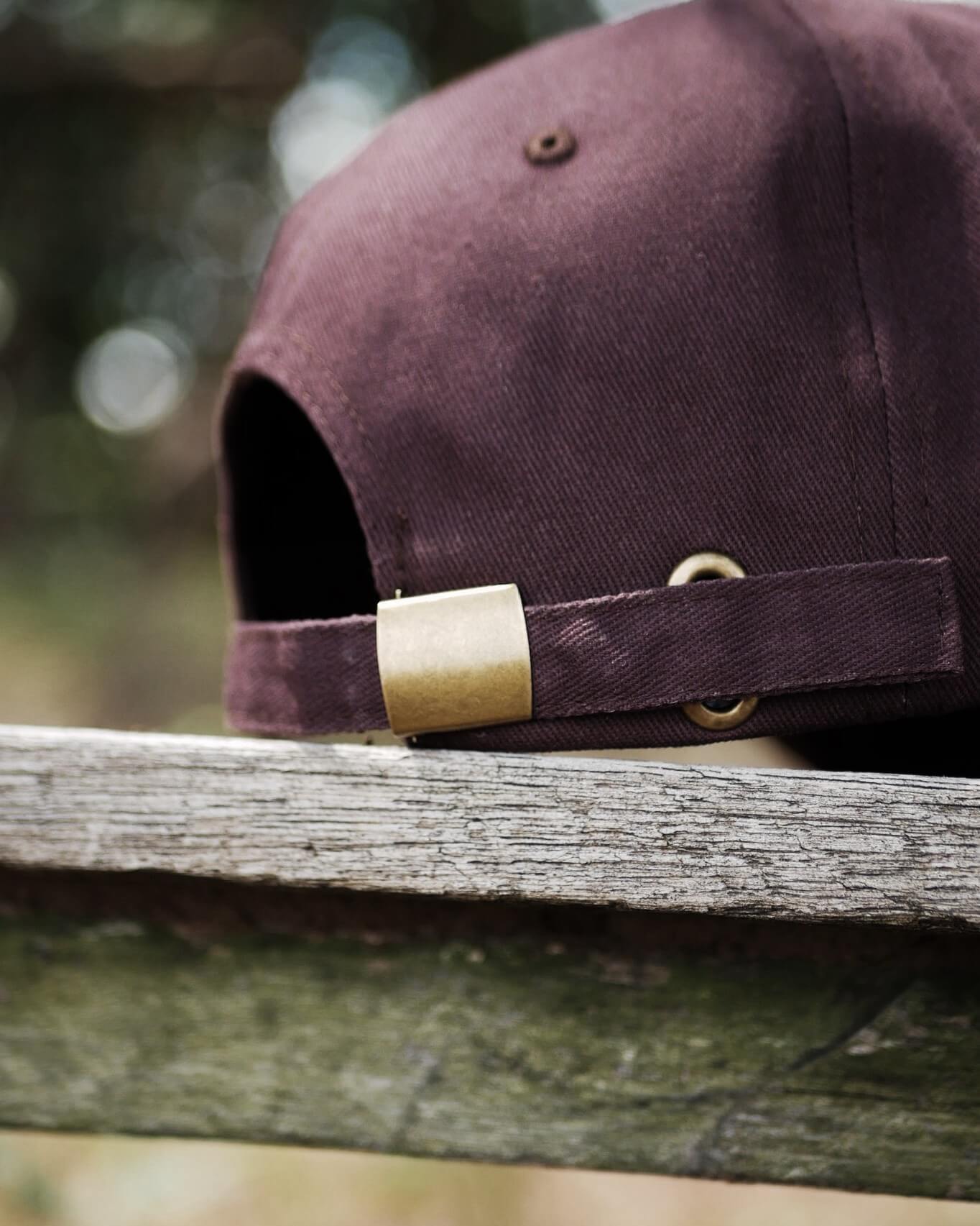 Brown cap with gold clasp on a wooden surface, blurred natural background