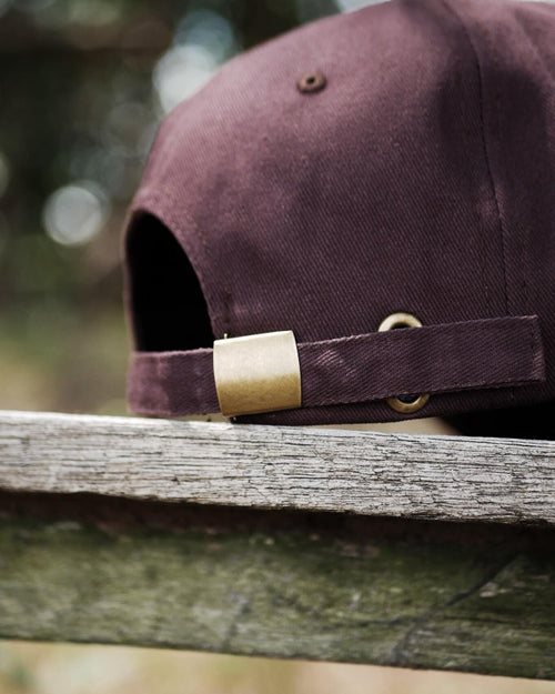 Brown cap with gold clasp on a wooden surface, blurred natural background