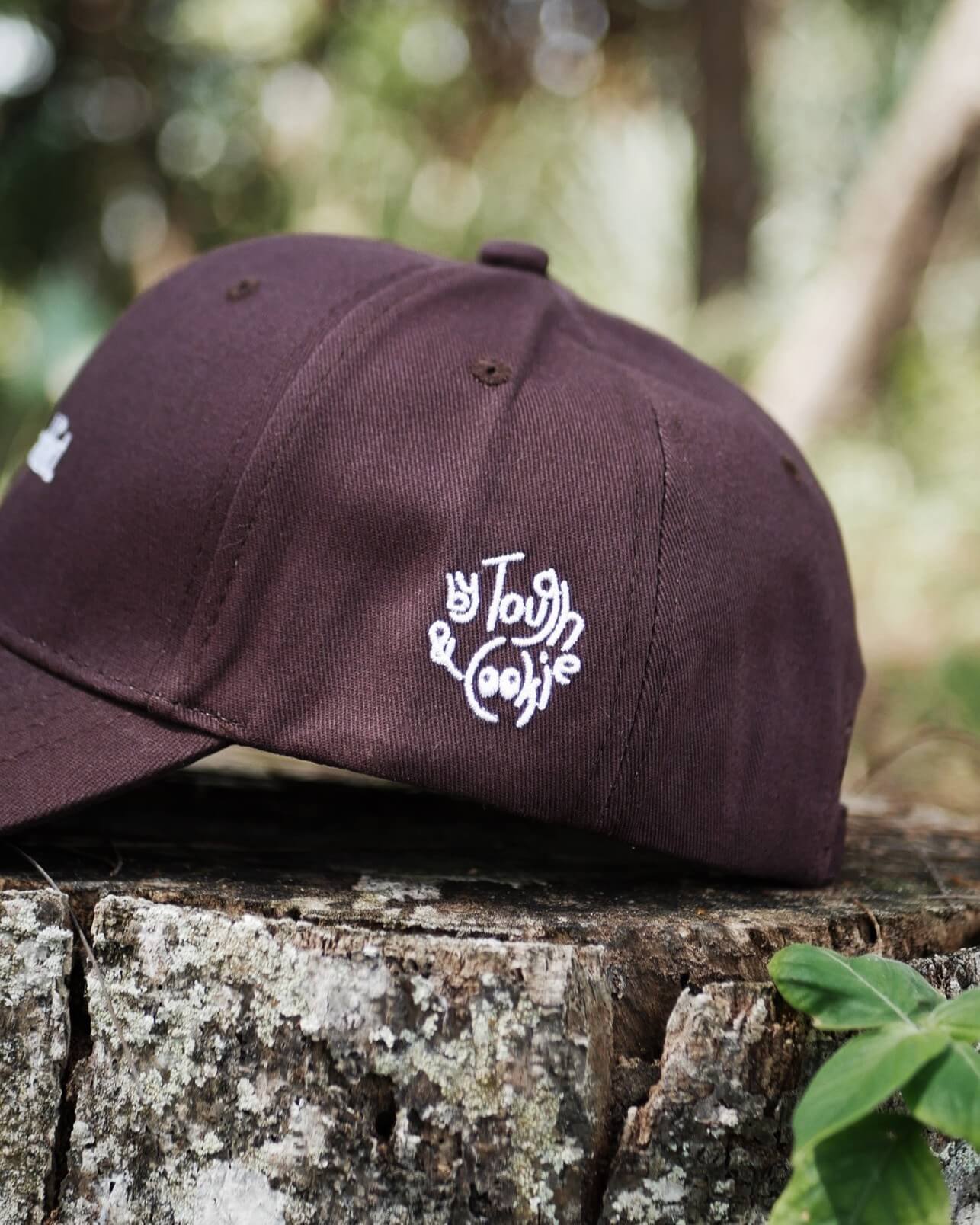 Brown cap with a logo on a wooden surface with a natural background