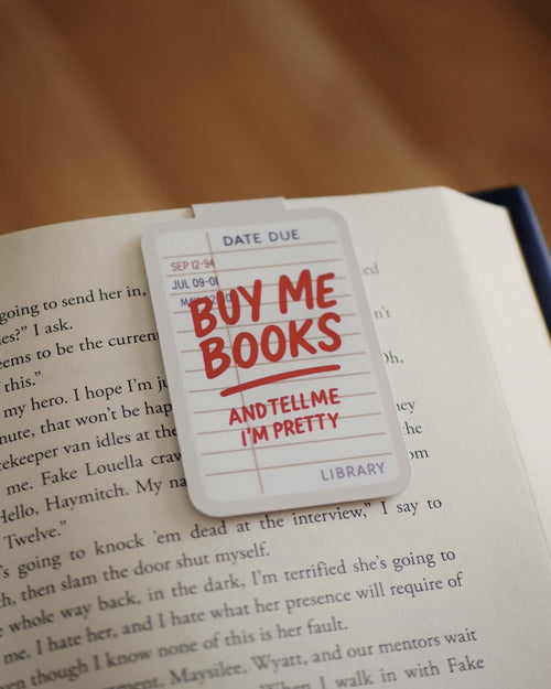 'Buy Me Books And Tell Me I'm Pretty' magnetic bookmark clipped on an open book.