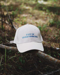 White cap with 'CEO of Overthinking' text on a branch in a natural setting