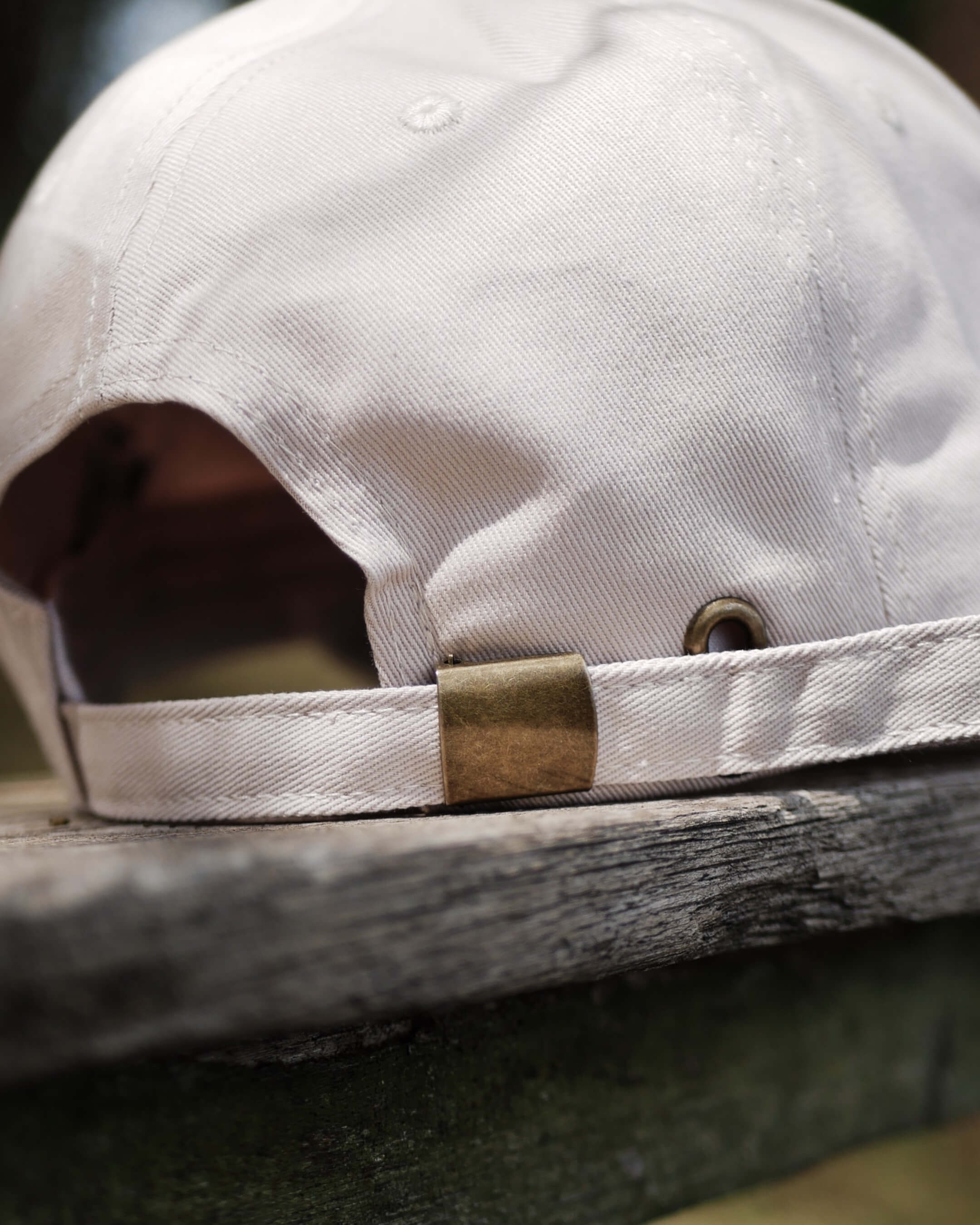 Close-up of a beige cap with a gold clasp on a wooden surface
