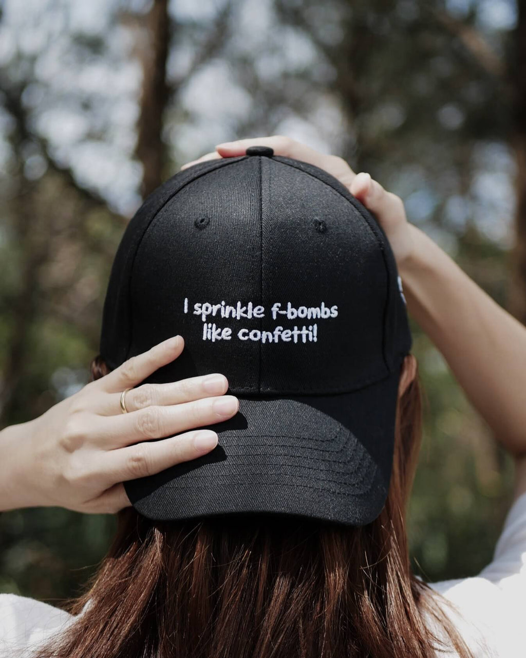 Person wearing a black cap with text, outdoors