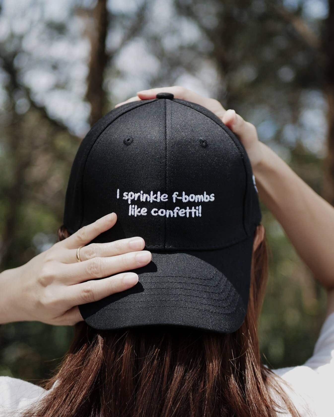 Person wearing a black cap with text, outdoors