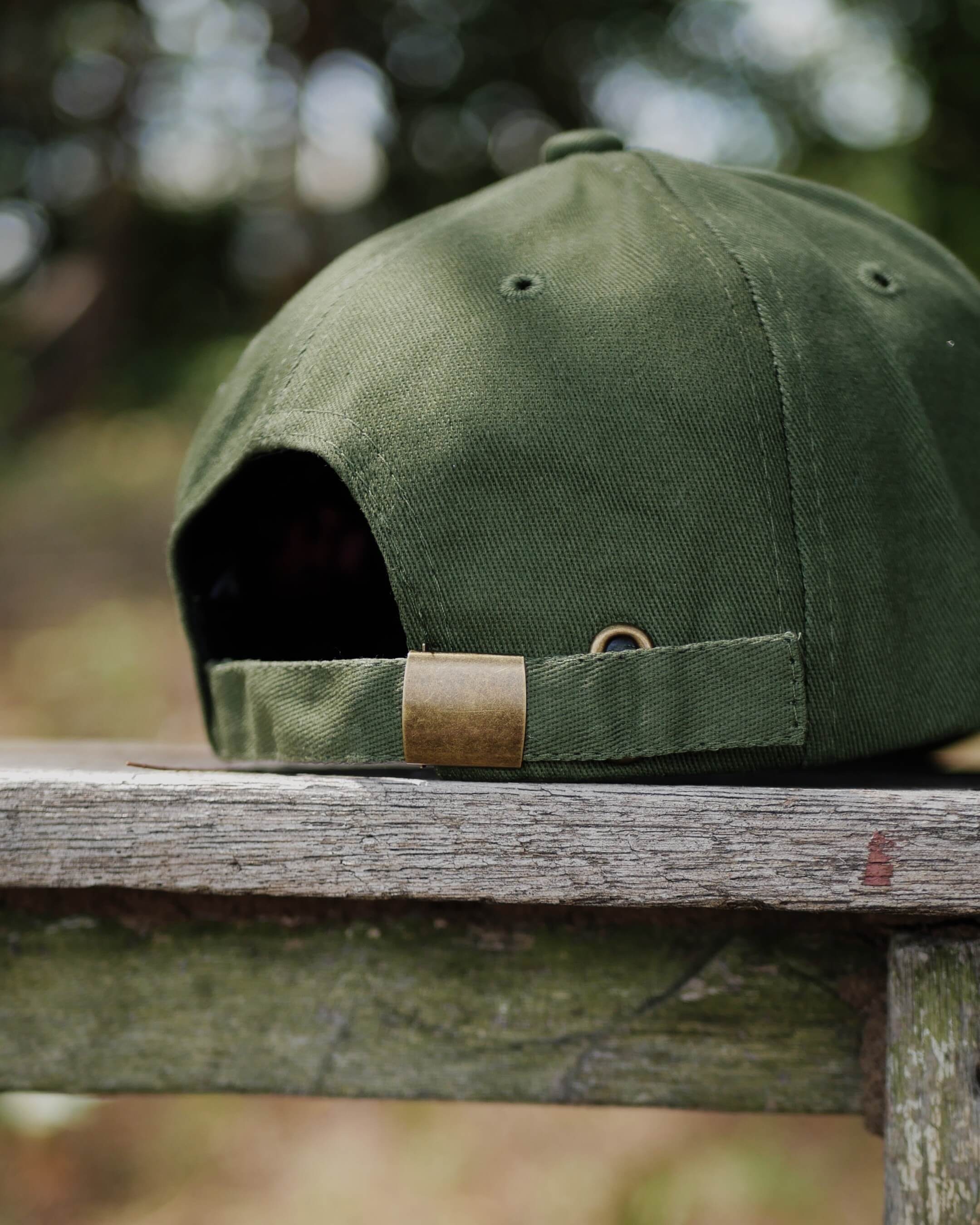 Green cap with gold clasp on a wooden surface outdoors