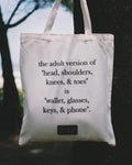 Tote bag with humorous text about adult essentials hanging on a tree