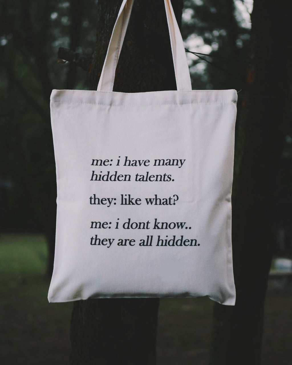 Tote bag with humorous text about talents held by a person outdoors