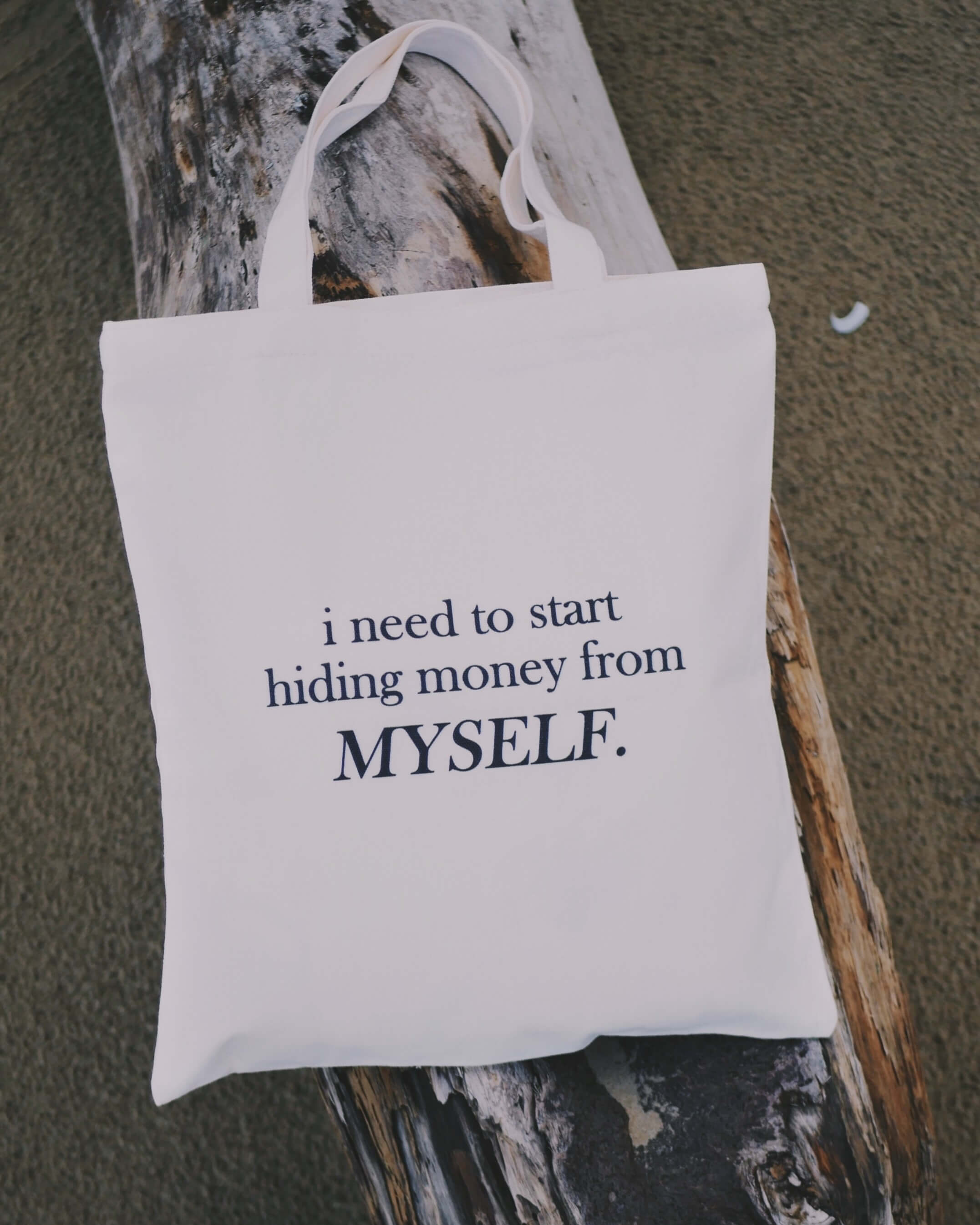 White tote bag with humorous text about "hiding money from myself"