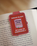 Magnetic bookmark with 'Emotional Support Book' design clipped on an open book.