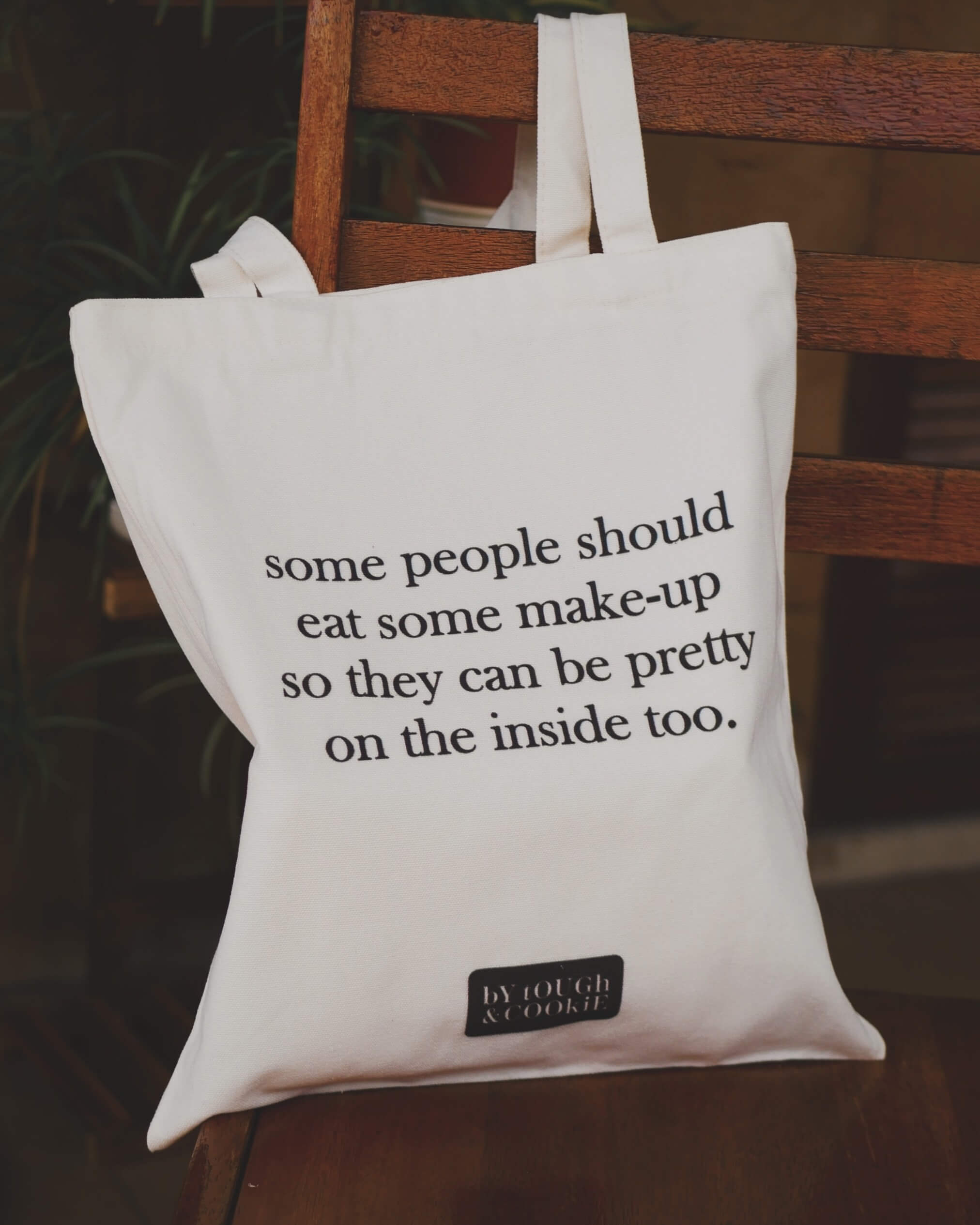 Tote bag with humorous text about fake people on a wooden chair