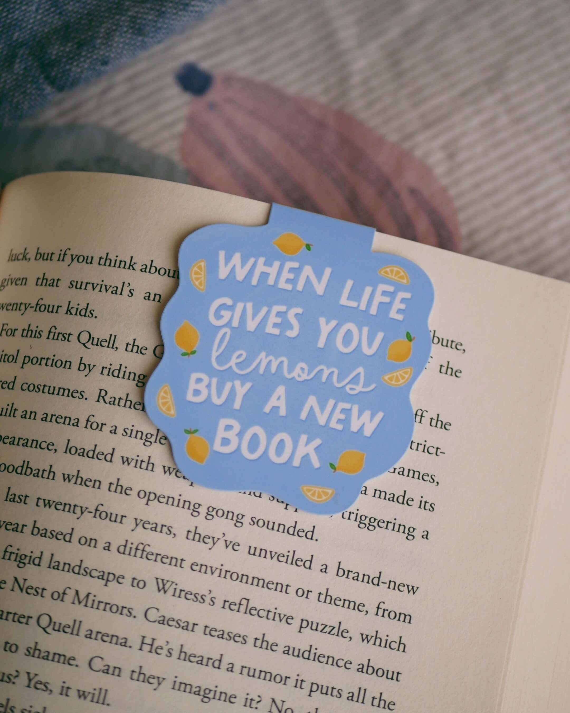 'When life gives you lemons, buy a new book' magnetic bookmark clipped on an open book.