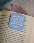 'When life gives you lemons, buy a new book' magnetic bookmark clipped on an open book.