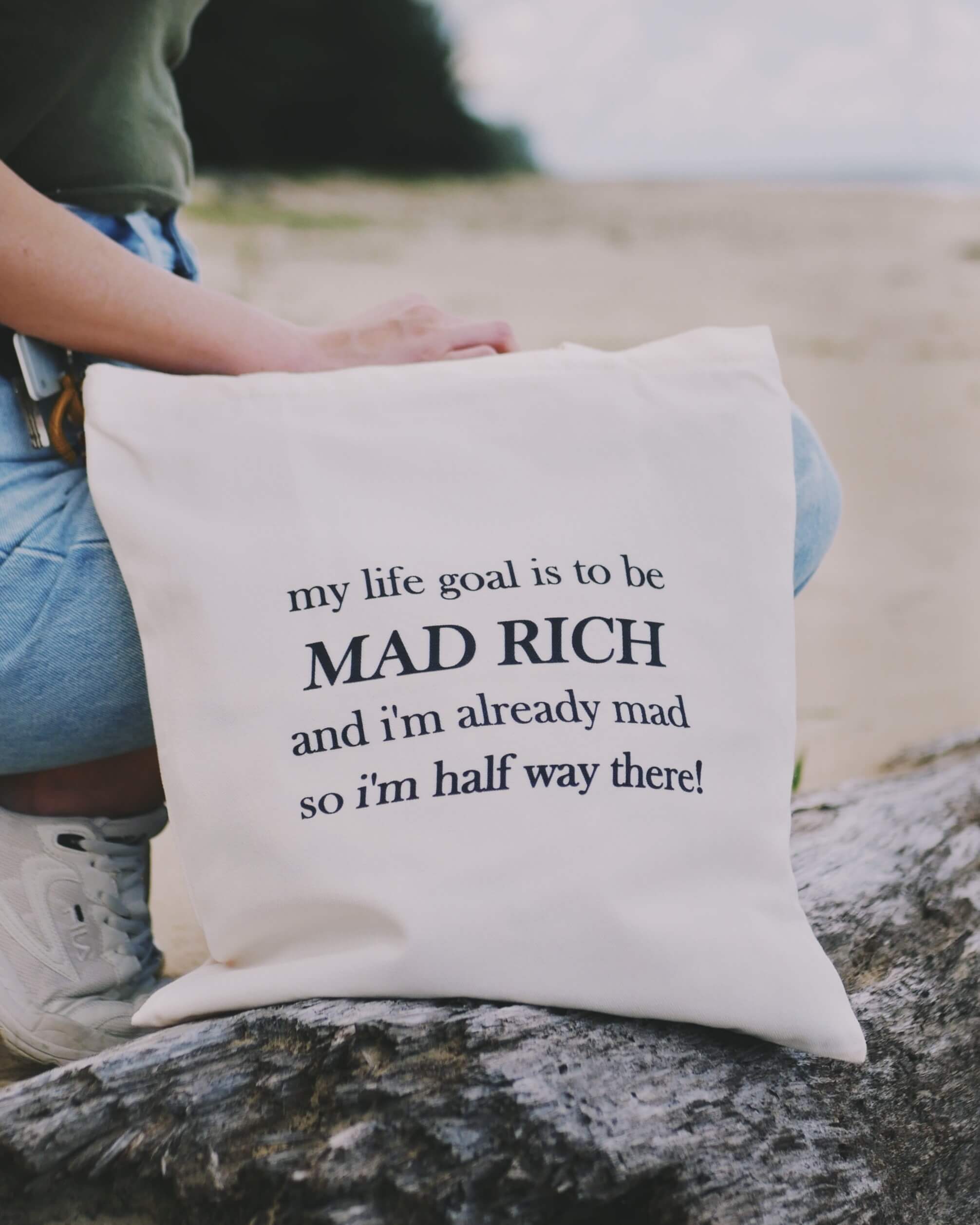 Tote bag with humorous text held by a person at the beach.