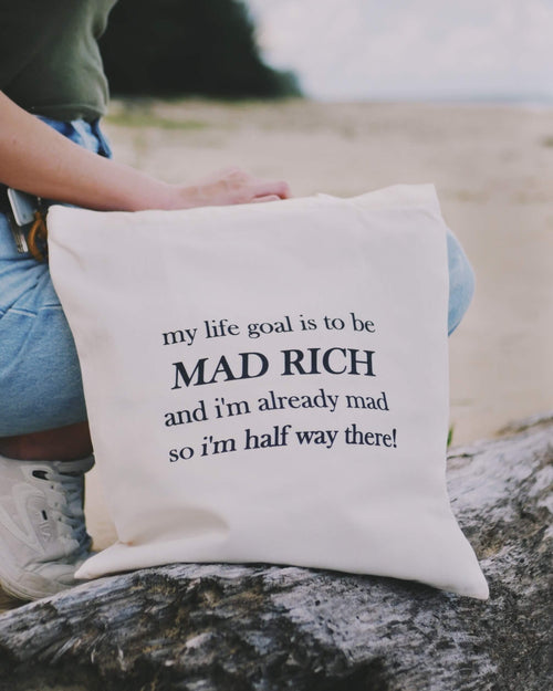 Tote bag with humorous text held by a person at the beach.