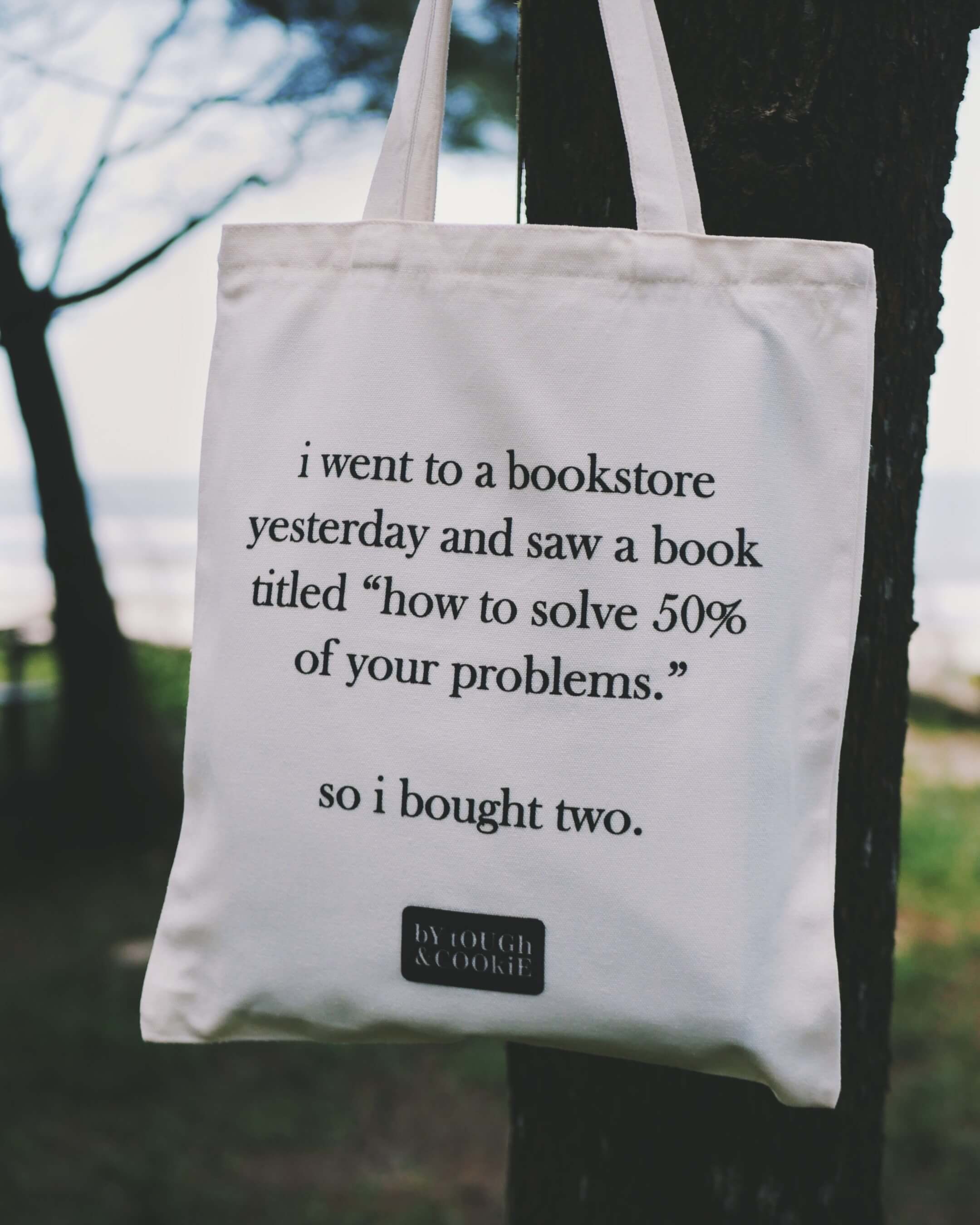 Tote bag with humorous text about a bookstore and books titled 'how to solve 50% of your problems'.