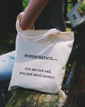 Tote bag with humorous text held by a person outdoors