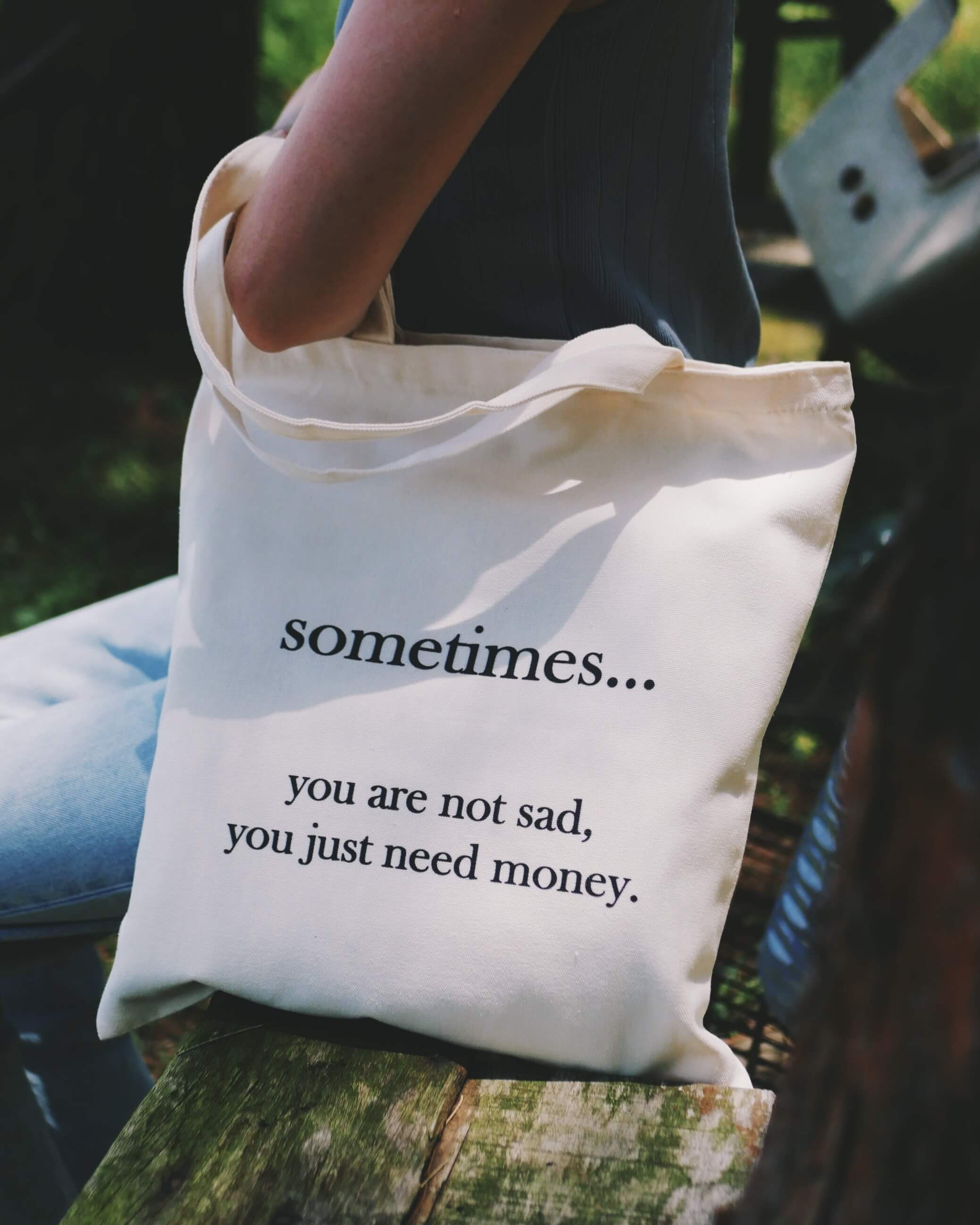 Tote bag with humorous text held by a person outdoors
