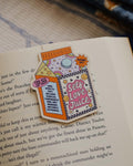 Magnetic bookmark with 'Self Love Juice' design clipped on an open book.