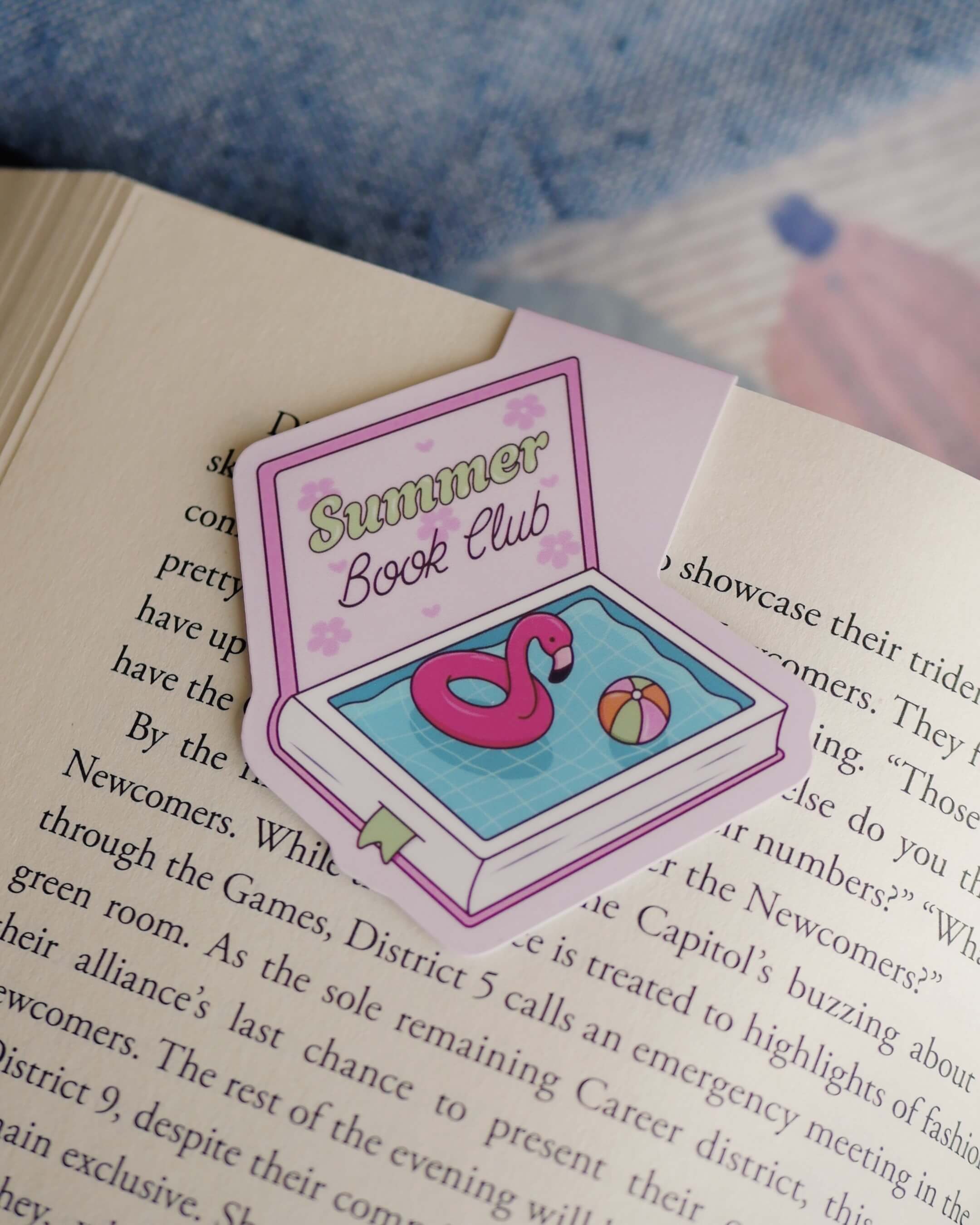 Summer Book Club magnetic bookmark with a pool design clipped on an open book