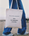 Person holding a tote bag with humorous text message on a beach.